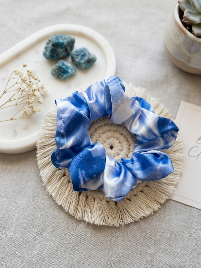 Blue silky scrunchie on a textured surface with decorative elements